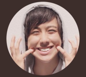 両手の小指を口角に当てる山内大輔
